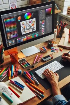 a person sitting at a desk with a computer and various colored pencils on it