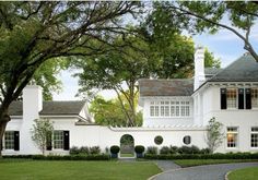 a large white house surrounded by trees and grass