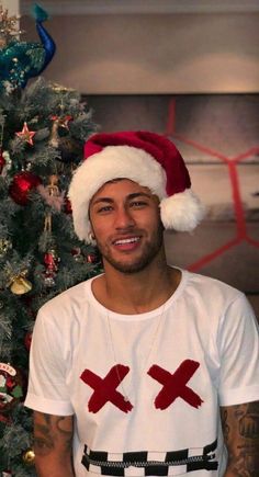 a man wearing a santa claus hat next to a christmas tree with ornaments on it