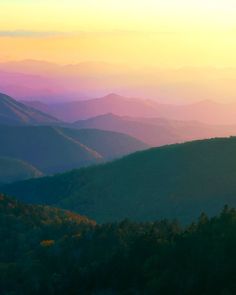 the mountains are covered in colorful hazes and light from the sun setting over them