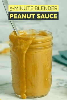 a jar filled with peanut sauce sitting on top of a counter next to a spoon