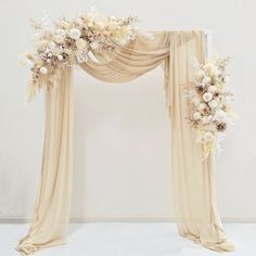 a wedding arch decorated with flowers and sheer drapes for an elegant touch to the ceremony