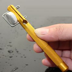 a person holding a yellow toothbrush in their hand with water droplets on the ground