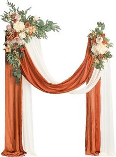 an orange and white wedding arch decorated with flowers, greenery and satin drapes