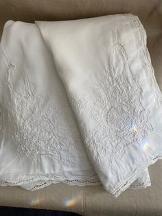 two white bedspreads sitting on top of a bed next to eachother