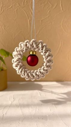 a christmas ornament hanging from a rope with a red bauble in the center