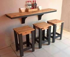 three wooden stools sitting next to each other in front of a table with bottles on it