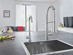 a stainless steel kitchen sink and faucet in a modern style home with large windows