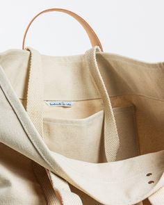 This Large East West Tote from Immodest Cotton is the perfect bag for weekend getaways and trips to the farmers market. With double stitched seams and removable leather handles, this cotton canvas shoulder bag converts to a handheld tote with ease. Not to mention - we love this neutral shade of canvas. Details + Design: Converts from handheld to shoulder with detachable leather handles. Remove the leather handles to wash. One interior pocket. Material: Cotton canvas. Undyed leather handles. Hand Levis Canvas Tote, Unique Hardware, Copper Hardware, Outdoor Textiles, Knit Shoes, Weekend Bag, Market Tote, Birthday Shopping, Childrens Gifts