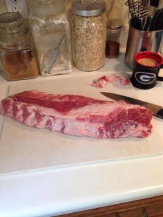 a piece of raw meat sitting on top of a cutting board next to a knife