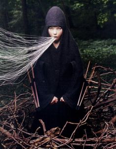 a woman sitting on top of a nest covered in white hair and long black veil