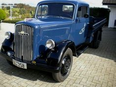 an old blue truck parked in front of a house