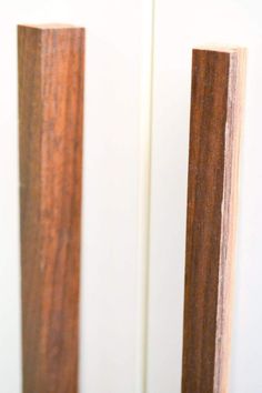 two pieces of wood sitting on top of a white wall next to each other in front of a door