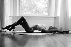 black and white photograph of a woman laying on the floor in front of a window