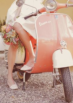 a woman sitting on top of a scooter with flowers in her hair and dress