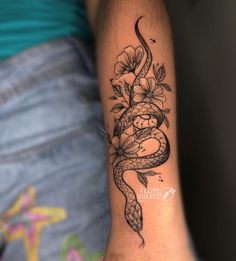 a woman's arm with a snake and flowers on it