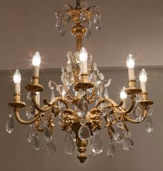 a gold chandelier with crystal drops hanging from it's center and four lights on each side