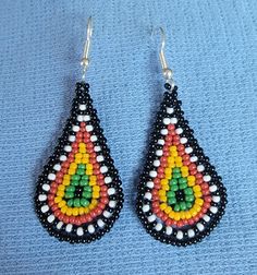 a pair of beaded earrings sitting on top of a blue cloth covered tablecloth