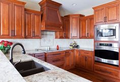 a kitchen with marble counter tops and wooden cabinets, stainless steel appliances and an oven