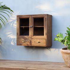 a wooden cabinet sitting next to a potted plant