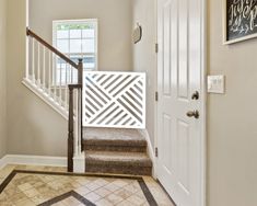 an entryway with stairs and tiled flooring next to a white door, window and framed artwork on the wall