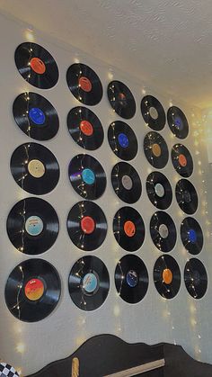 a wall mounted to the side of a room filled with vinyl records and string lights