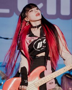 a woman with long red hair playing an electric guitar