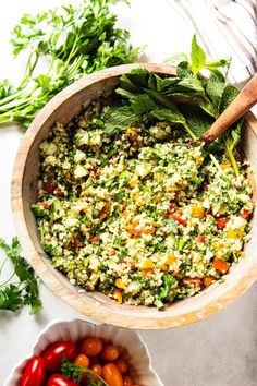 a wooden bowl filled with lots of food next to other vegetables and herbs on top of a table