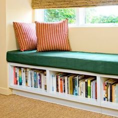 a window seat with books on it in front of a book shelf filled with books