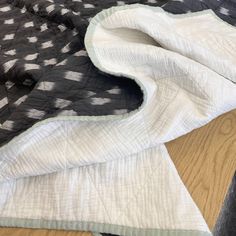 a black and white quilt laying on top of a wooden floor