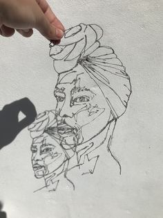 a drawing of a woman's face is being drawn on the wall by someone