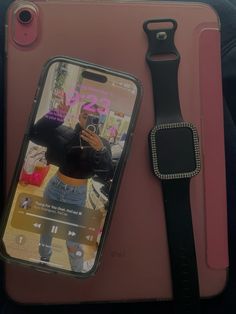 an iphone case with a cell phone attached to it, sitting next to a watch