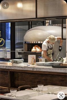 a man cooking in a restaurant kitchen with an open fire place behind him and on the counter