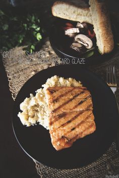 grilled sandwich and mashed potatoes on a black plate with silverware next to it