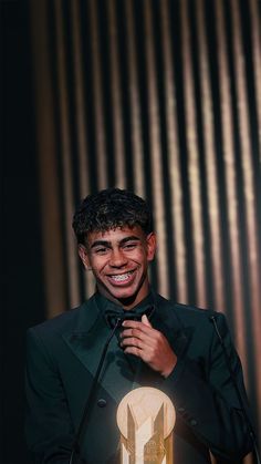 a man in a tuxedo is smiling while holding a microphone