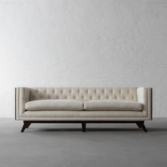 a white couch sitting on top of a cement floor next to a white brick wall