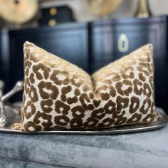 a leopard print pillow sitting on top of a metal tray