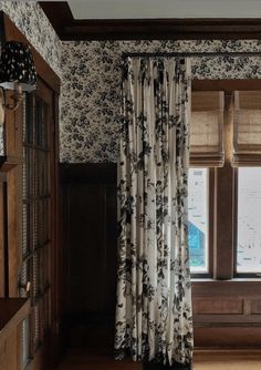 the curtains are pulled back in front of the window with floral print on it, along with wooden shelves and windowsills