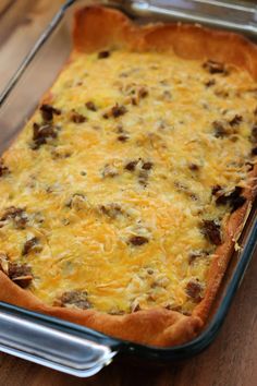 a casserole dish with cheese and sausage in it on a wooden table top