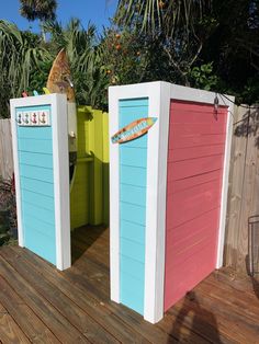 two beach huts with surfboards on top of them sitting on a wooden deck next to a fence