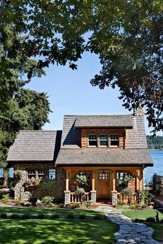 a small wooden house sitting on top of a lush green field next to a lake