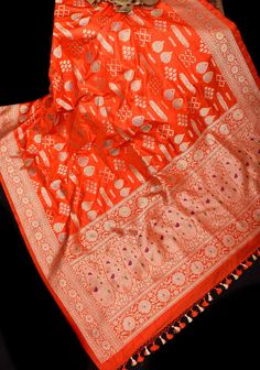 an orange and white banaram saree on a black surface with other items