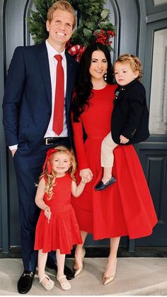 a man and two children standing in front of a door with a christmas wreath on it