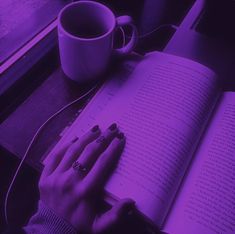 a person sitting at a table with an open book and cup of coffee in front of them