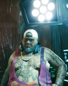 a tattooed man with headphones on standing in front of a light