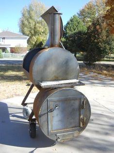 a large metal oven sitting on the side of a road next to a tree filled yard