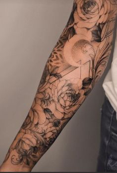 a man's arm with flowers and an arrow tattoo on the left side of his arm