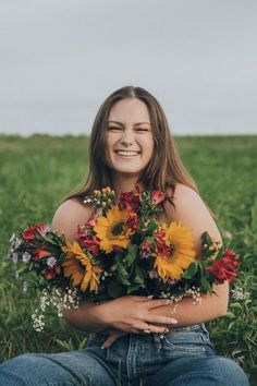 a woman sitting in the grass holding flowers