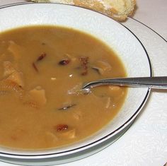 a white plate topped with soup next to a piece of bread