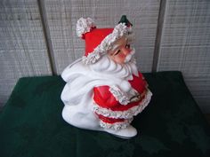 a ceramic santa clause figurine sitting on top of a green tableclothed surface